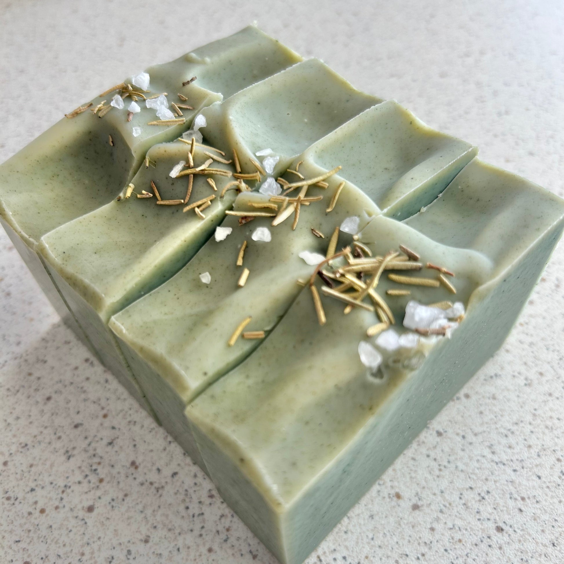Green soap bar with decorative elements on a light gray surface
